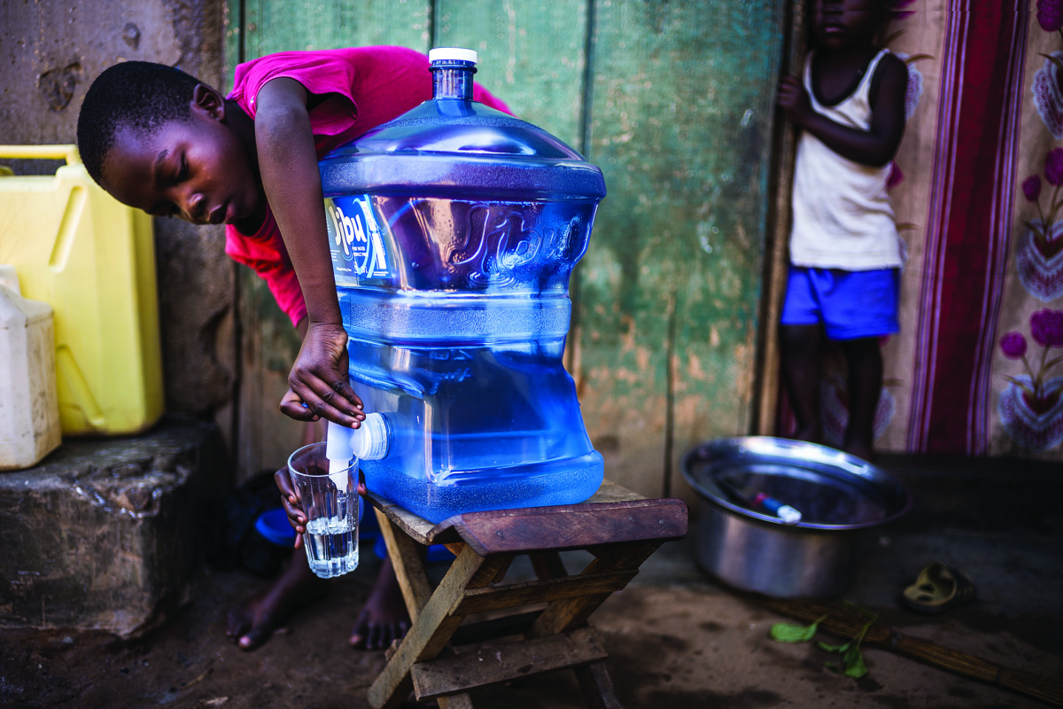 Boy pours cup of water from Jibu jug