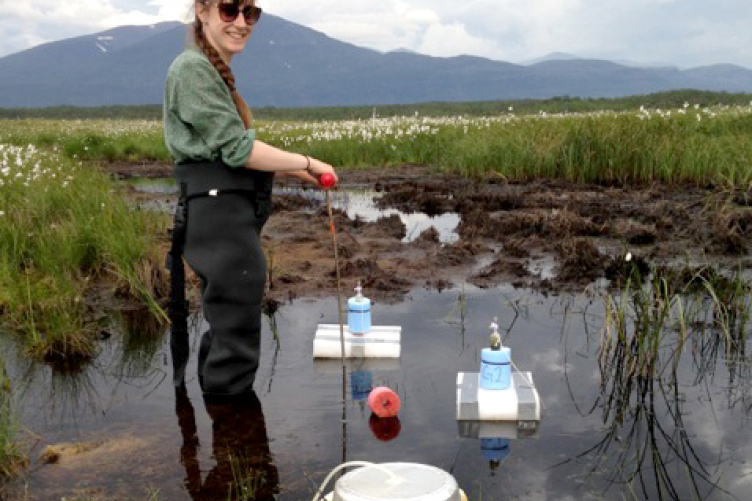 Young researcher in waders takes samples in a wetlands