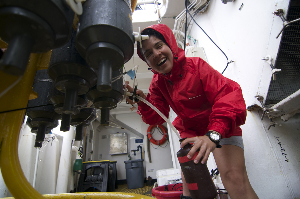 Melissa Melendez wearing a red raincoat working on a wet piece of research equipment