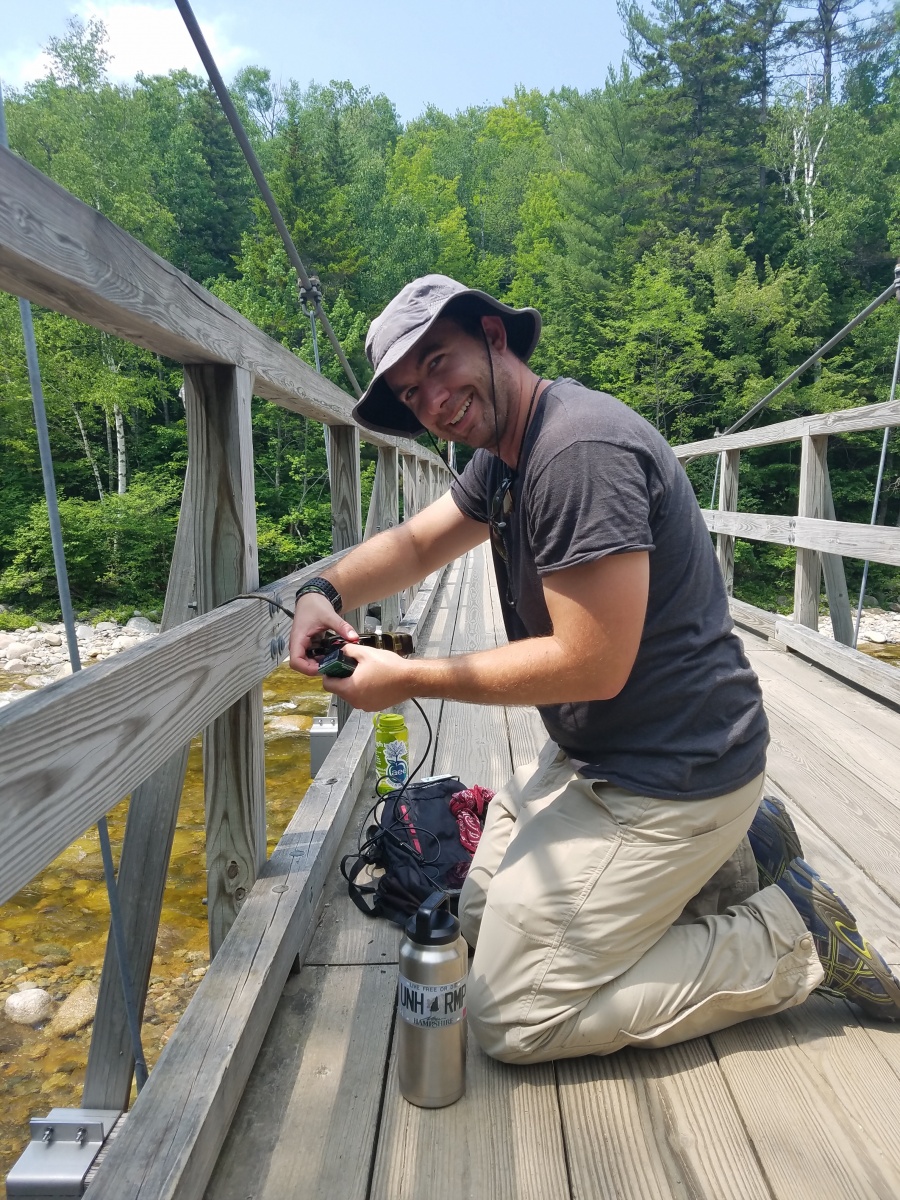 UNH researcher deploying research equipment on trail