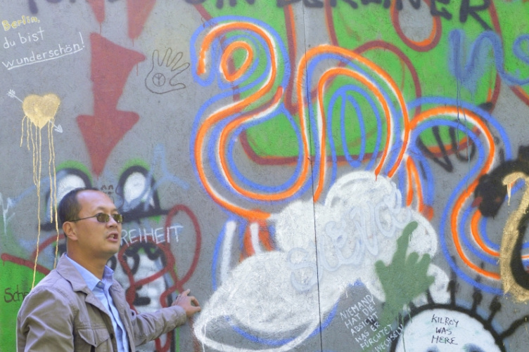 Ben Cariens stands in front of the replica Berlin Wall in Murkland Courtyard.