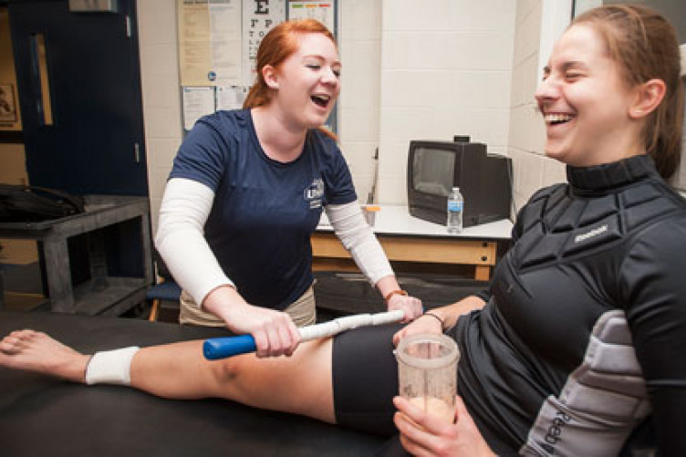 student performs atheltic therapy on hockey player