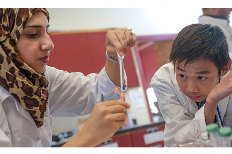 UNH Manchester biololgy teaching assistant Zaynav Mahmod from Jordan assists Tan Dao from Vietnam precipitate his DNA sample during UNH Manchester's Summer EXCELL Program.