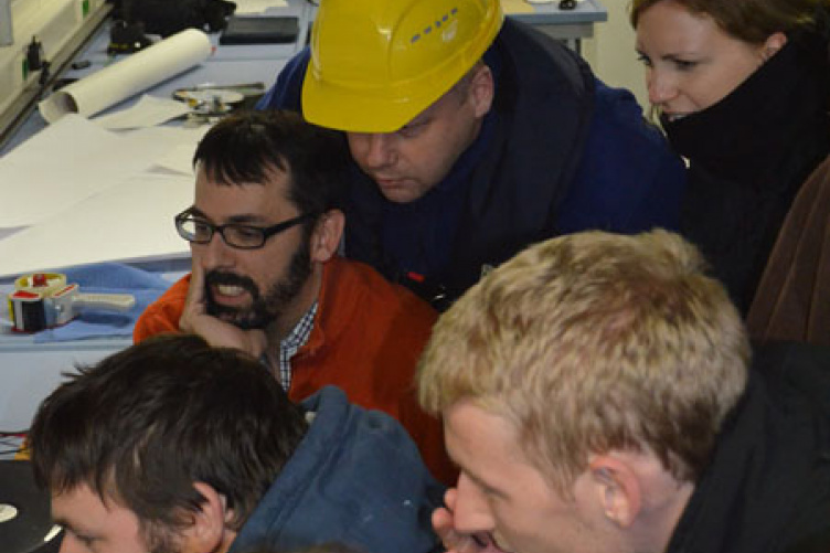 Jonathan Beaudoin (in glasses and orange sweater), research assistant professor in the University of New Hampshire’s Center for Coastal and Ocean Mapping/Joint Hydrographic Center, views the underwater footage of the S.S. Terra Nova with others onboard the Schmidt Ocean Institute’s R/V Falkor.