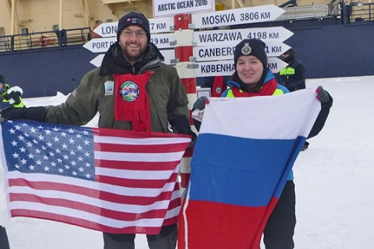 Researchers Kevin Jerram and Evgenia Bazhenova at the North Pole, with American and Russian flags
