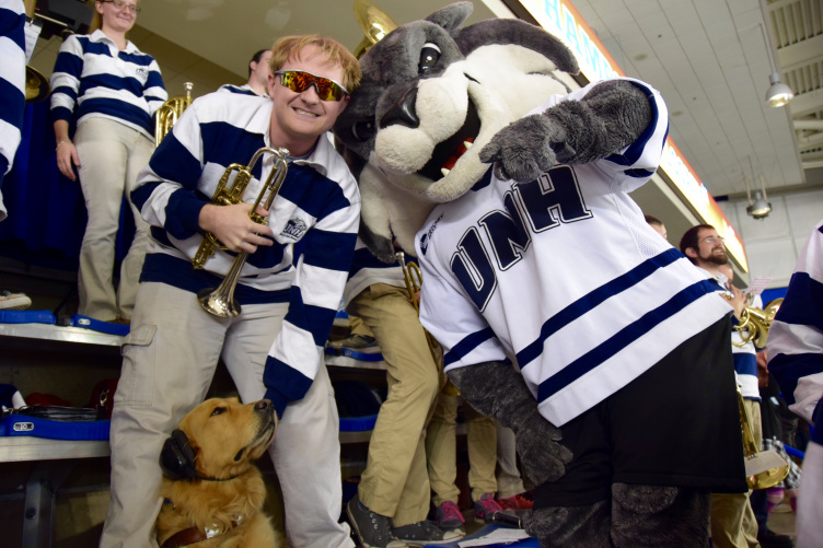 Travis Nevins '17 poses with his guide dog Mathis at a UNH hockey game.