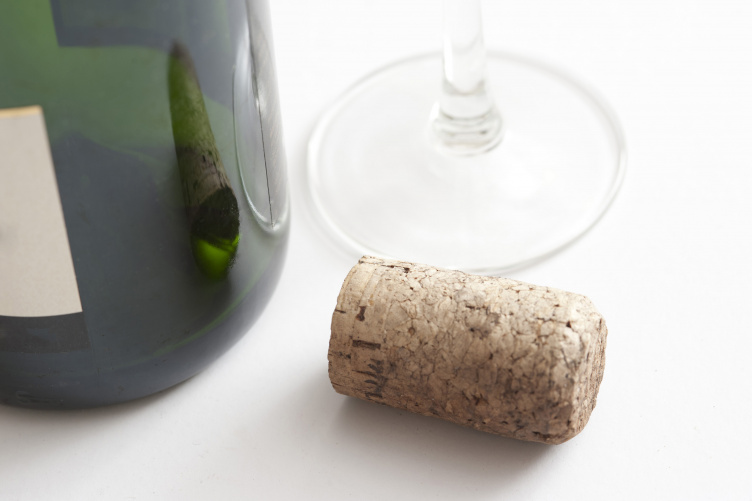 A wine bottle and cork next to a wine glass