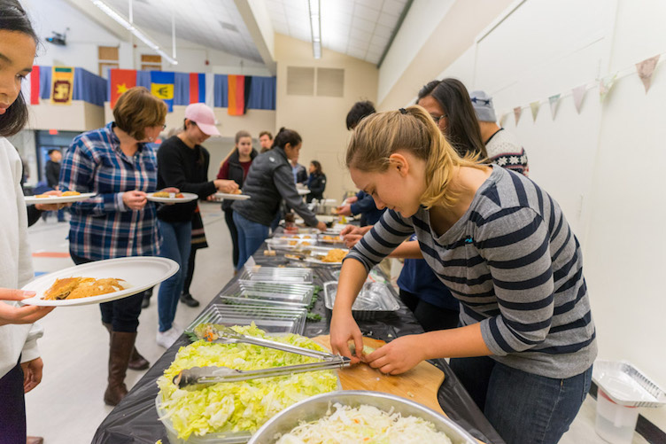 students serving food at international luncheon