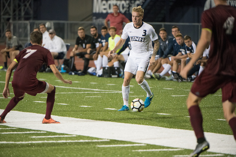 A member of the men's soccer team moves the ball downfield. 