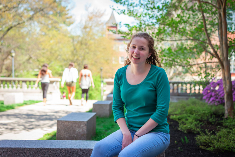 UNH's Allison Lehoux '18 sitting on a bench outside of James Hall at UNH