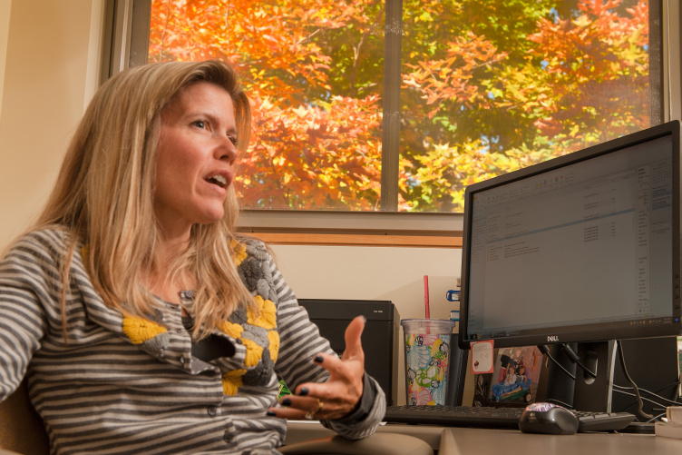 Corinna Tucker sits at a computer in front of a window