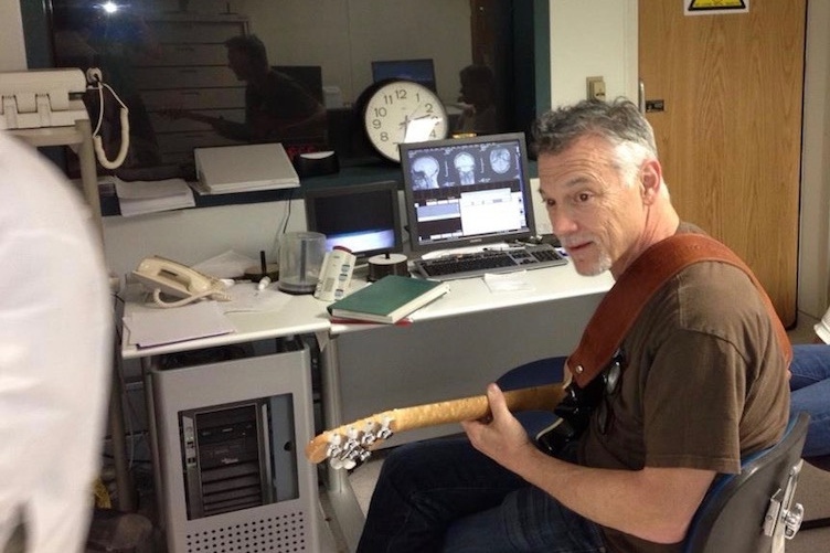 Professor Don Robin playing the guitar while subject undergoes brain scan.