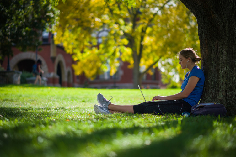 A UNH student sitting against a tree on the Durham campus