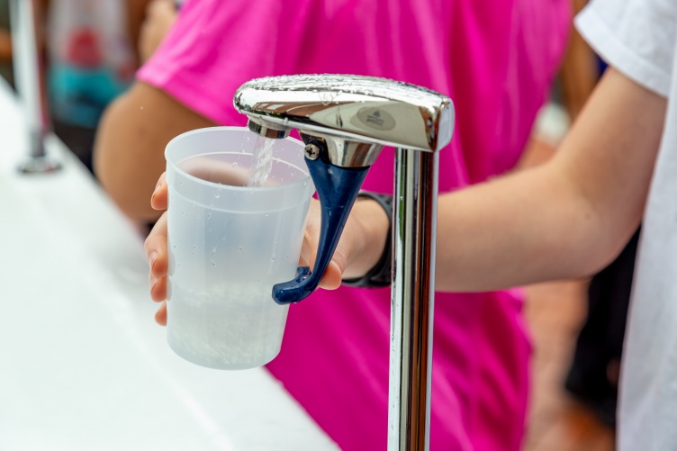 Filling a plastic cup with drinking water at a fountain