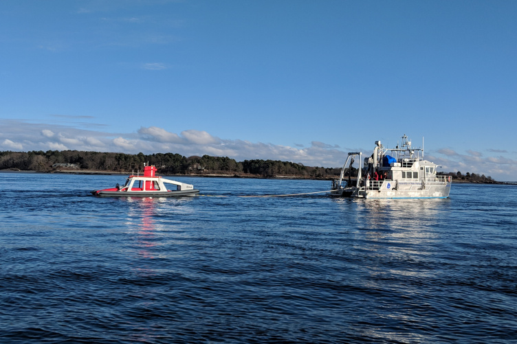 Autonomous surface vehicle at sea behind a research vessel