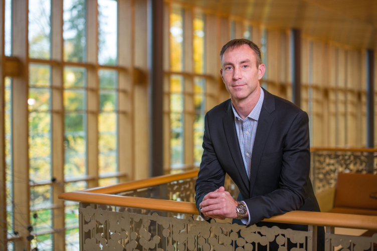 Assistant Professor of Organizational Behavior Michael Kukenberger posing next to railing