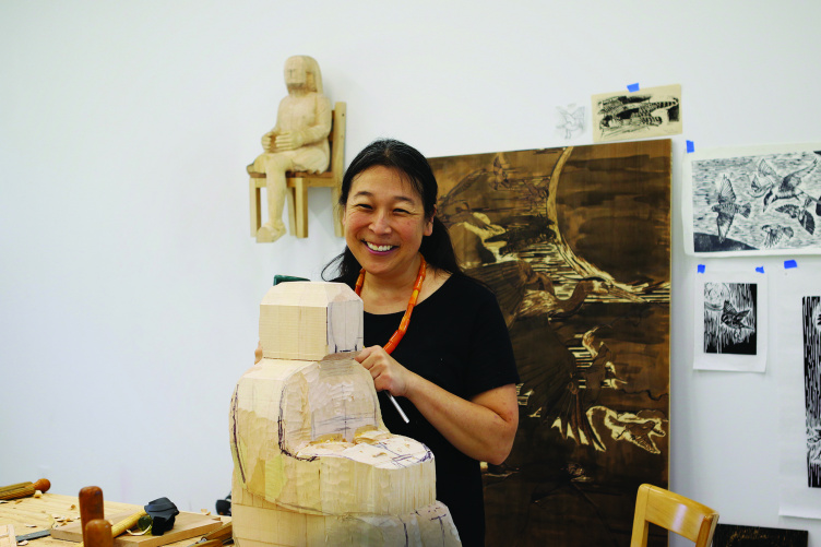 Sachiko Akiyama works on a large wood sculpture