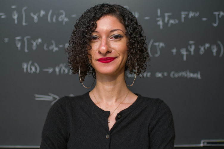 Chanda Prescod-Weinstein stands in front of a chalkboard with equations