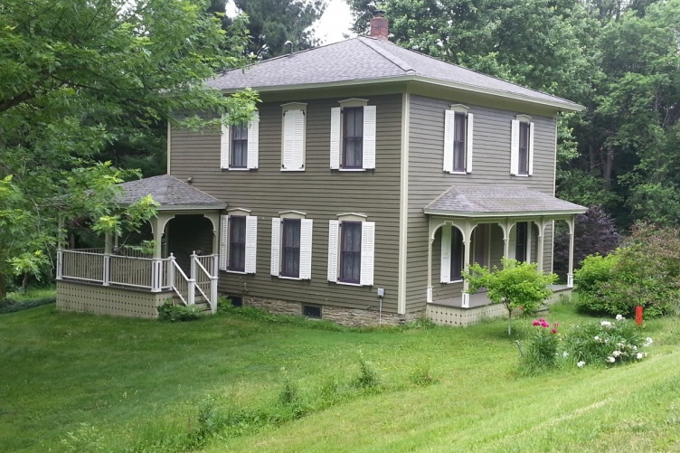 Grey house surrounded by green lawn. 