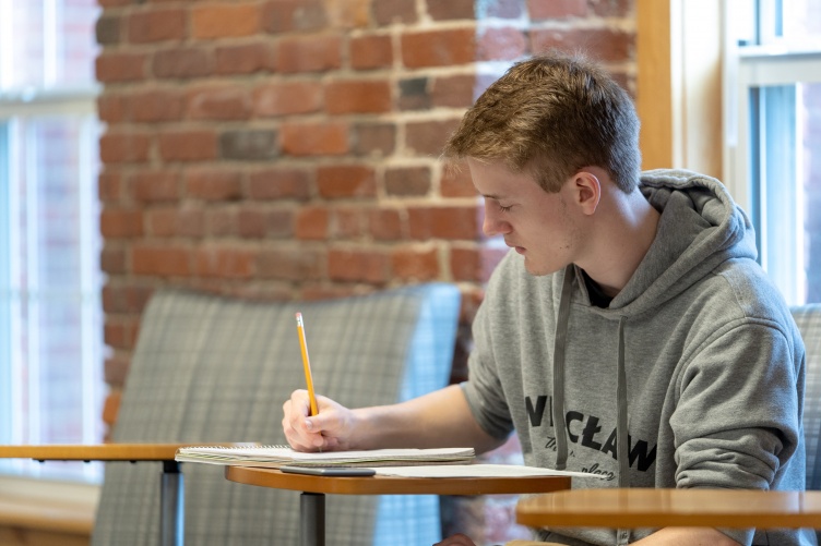 UNH Manchester student writing in the student commons