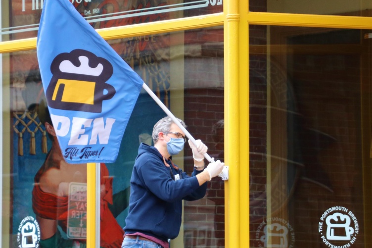 A Portsmouth store owner puts out an open for business sign