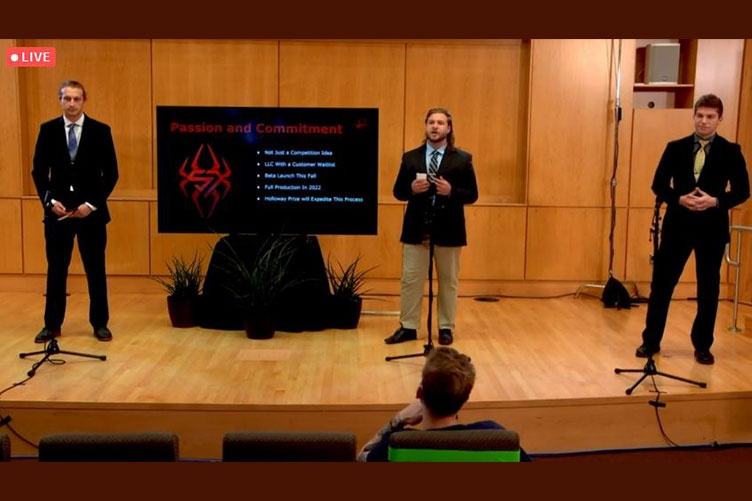 3 students presenting on a stage