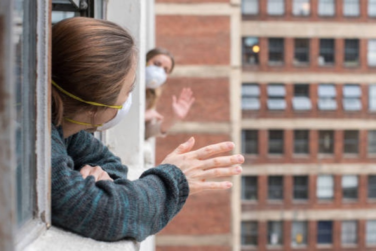 Image of women waving outside their windows with masks
