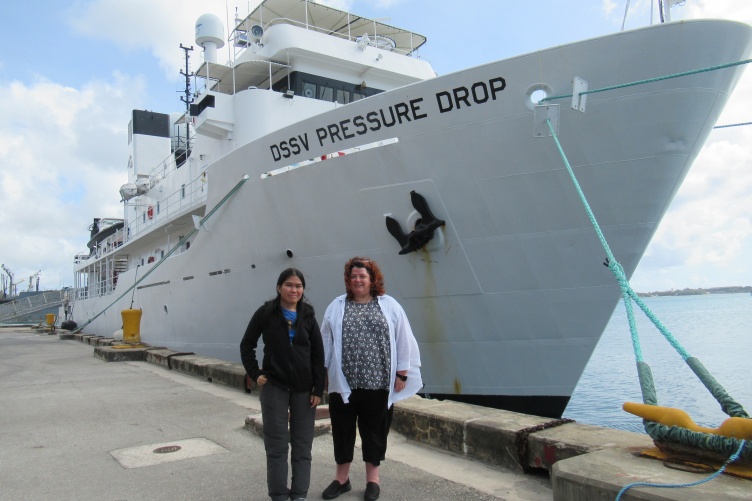 Jaya Roperez and Rochelle Wigley stand on a dock in front of the DSSV Pressure Drop vessel.