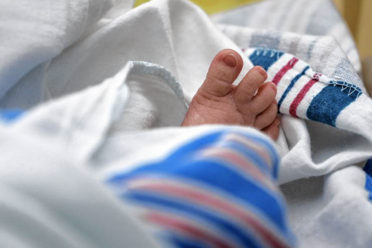 A newborn lays in the hospital wrapped in a blanket.