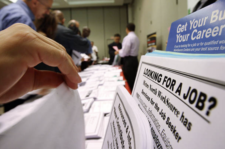 A man searches through a pile of unemployment forms