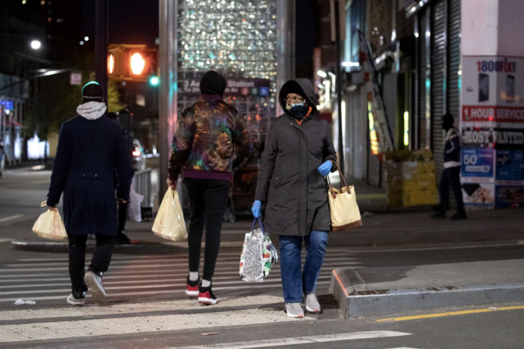 People cross a quiet intersection in the Bronx borough of New York