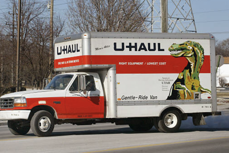 A U-Haul truck drives on a rural, winter road