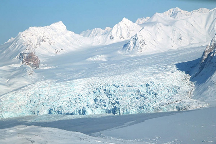 A small glacier and snow-covered mountains in Svalbard, Norway.