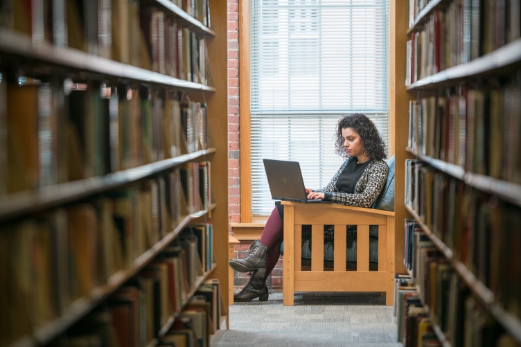 UNH online MBA student studying in the library