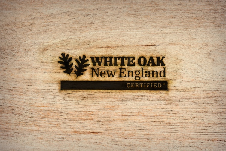 Logo with leaves and words "White Oak New England Certified" are branded on piece of wood