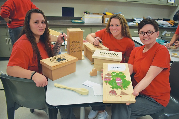three women in classroom showing their woodworking projects