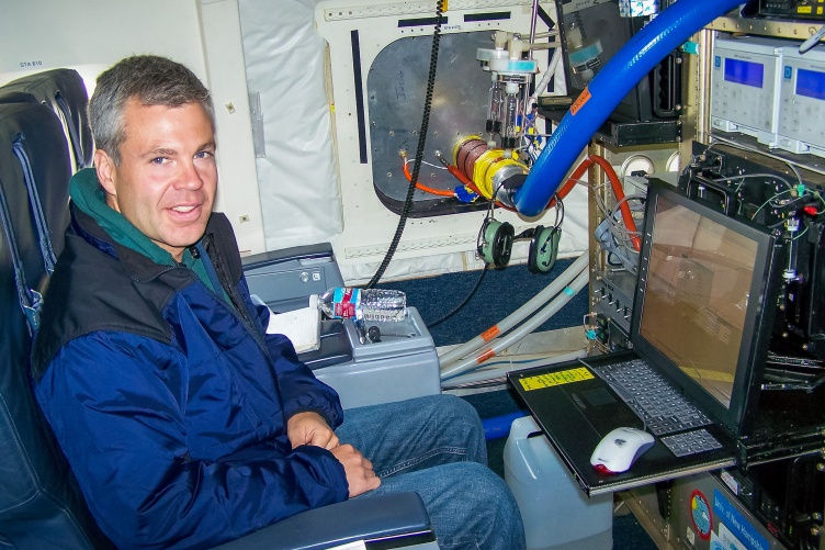Eric Scheuer sits on an airplane in front of a laptop and data instruments.