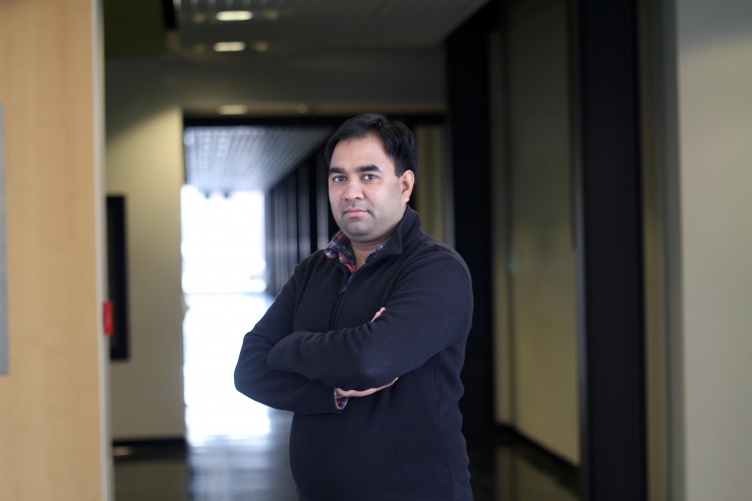 Researcher Harish Vashisth stands with arms crossed in darkened hallway
