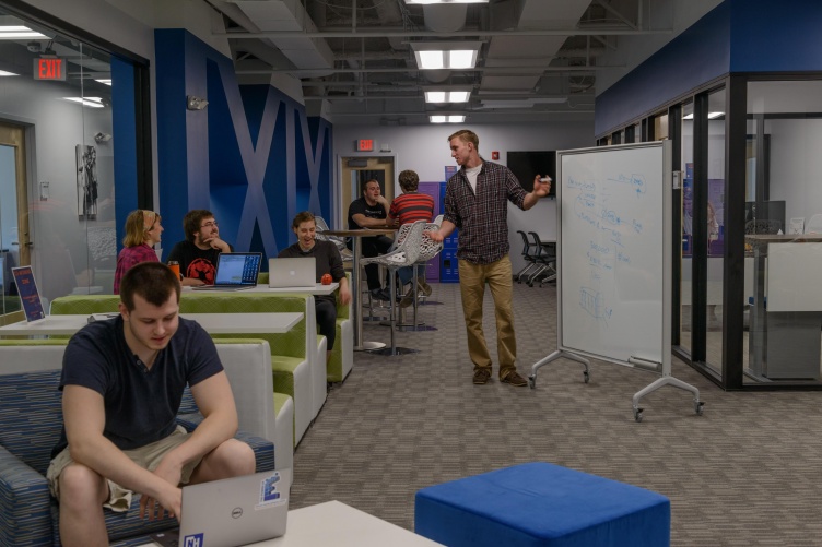 Students work at desks and a white board in a clean, modern space
