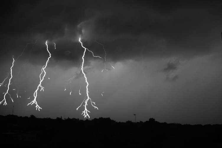 Black and white image of three lightning strikes next to one another.