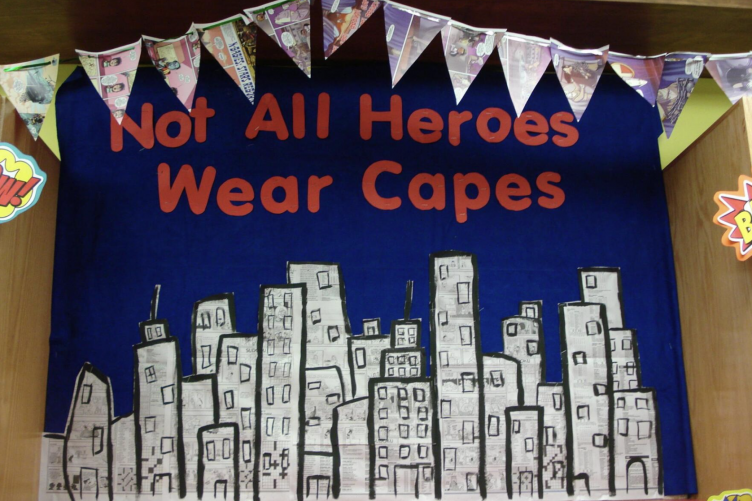 A library display with the words "Not All Heroes Wear Capes" showing a cityscape
