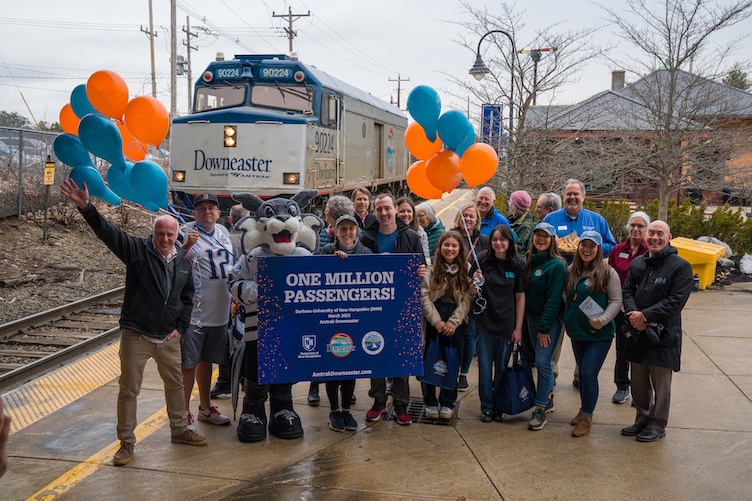 Train No. 684 arrives behind a group celebrating the 1 million rider milestone