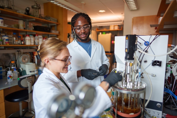 Two students work in a lab using advanced instrumentation.