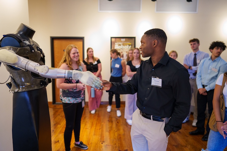 Student shaking hands with robotic prosthetic arm