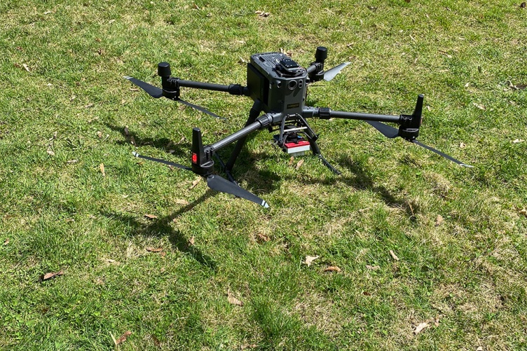 A photo of an unpiloted aerial drone sitting on a grass field.