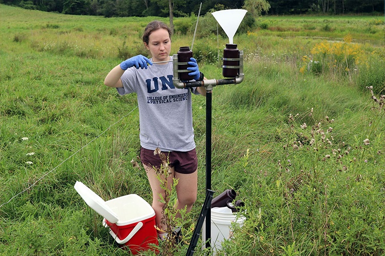 A woman gathers rain samples in a field