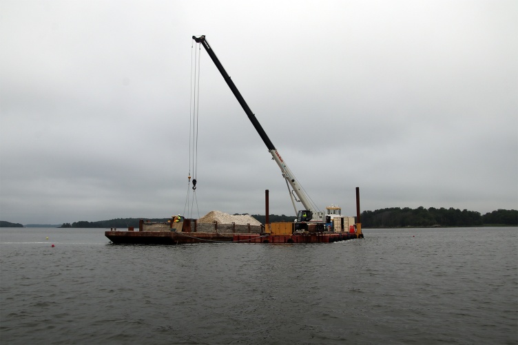 A barge floats on the water at the Nannie Island reef restoration site in Great Bay Estuary.