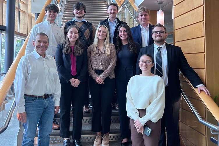 Aidan Hughes '24 stands with a group of people on a stairway in Paul College