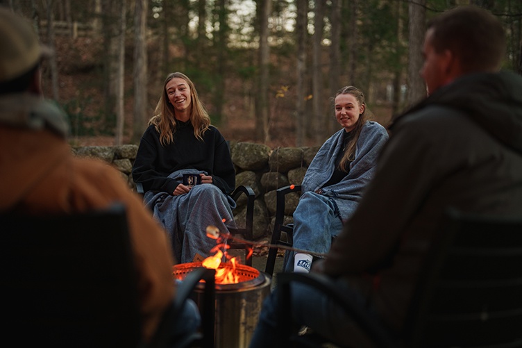 Two female students gather around a campfire
