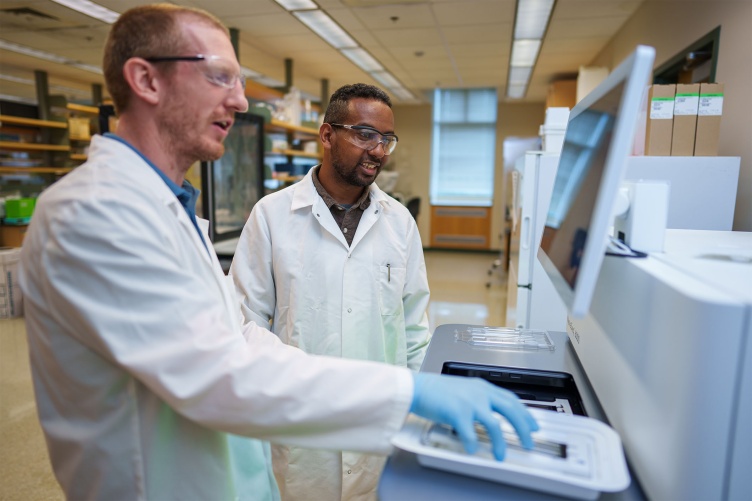 A photo of two men working on a sequencing machine together at the Hubbard Center for Genome Studies.